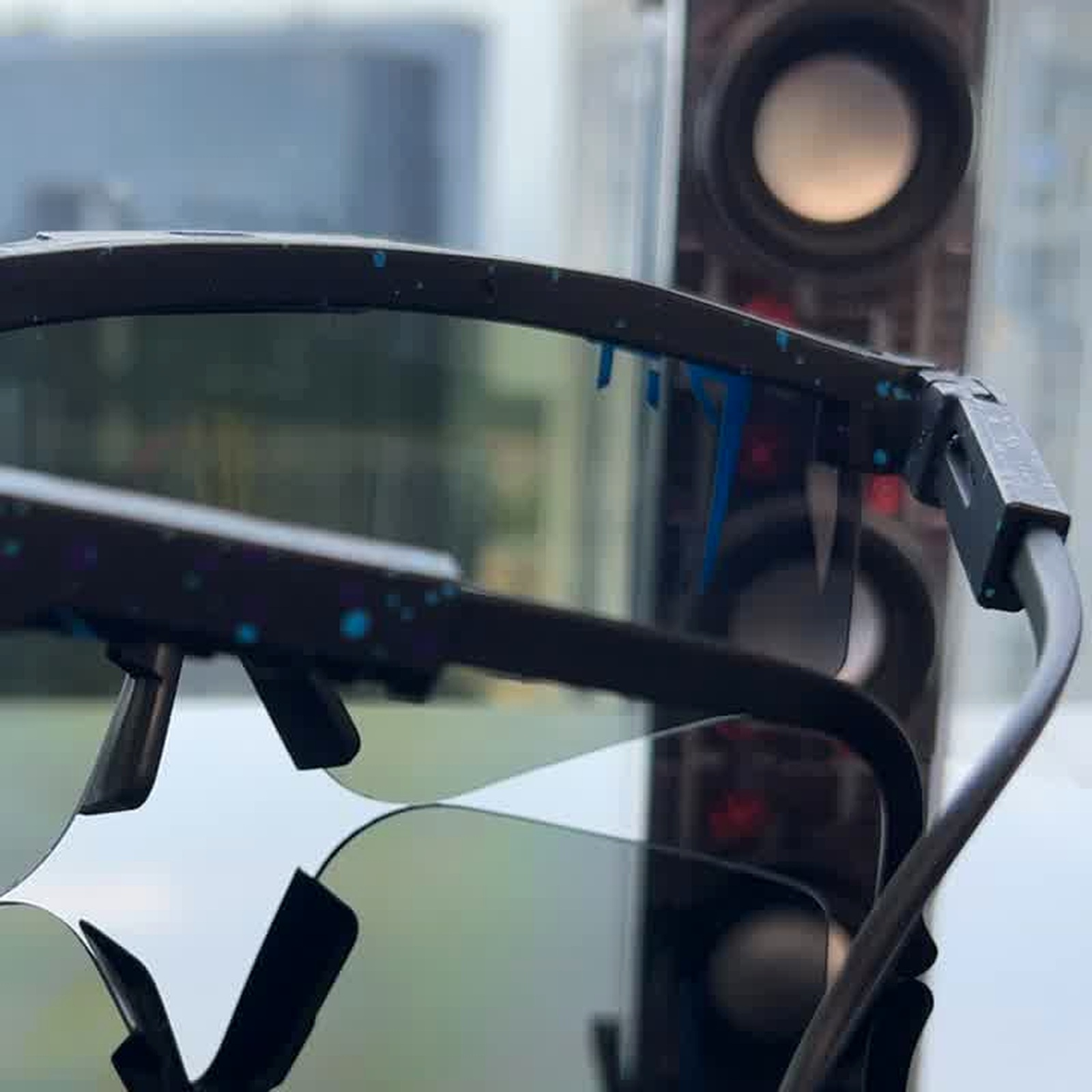 Close-up of VeloVisor AeroShield Pro TR90 temple arms and nosepiece on a bicycle handlebar showing flexible frame and shield lens curvature